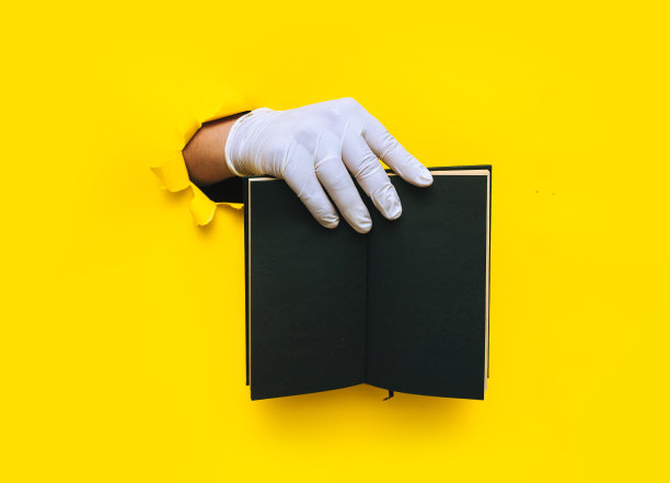 一位医生戴着白色乳胶医用手套，右手拿着黄色背景的黑色手工笔记本。撕纸与复印空间，模拟。概念文本放置，黑名单。图片下载