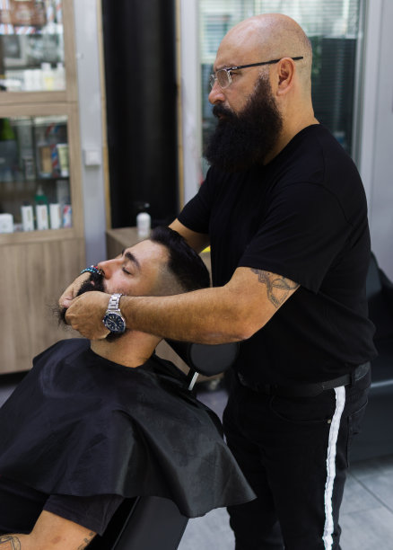 成熟的男性理发师按摩客户的脸图片下载