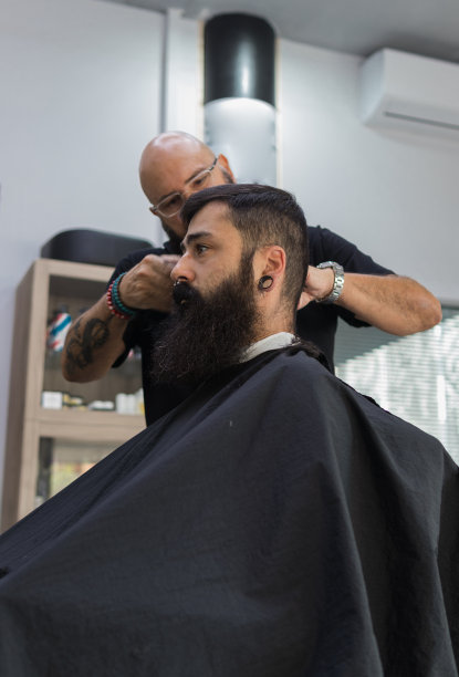 顾客坐在一个座位上，一位男理发师正在给他理发图片下载