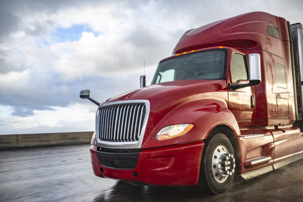 红色大钻机引擎盖半挂车与干货车半挂车运行在宽阔的公路在暴风雨天气图片下载