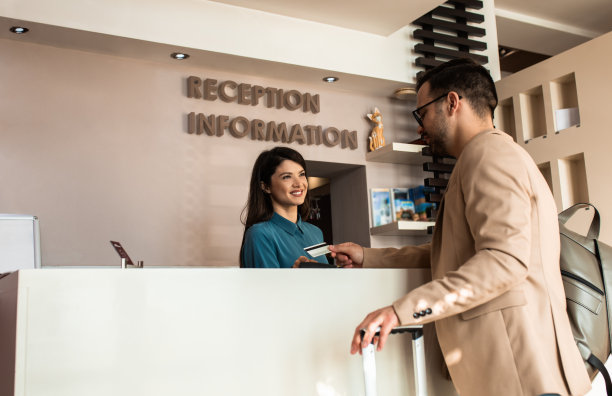 客人在接待处用信用卡向女接待员支付住宿费。图片下载