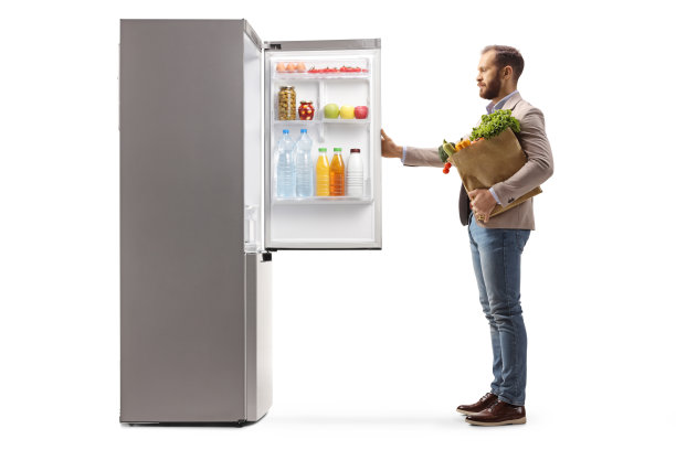 一个男人打开冰箱，拿着一个杂货袋的全身剖面图图片下载