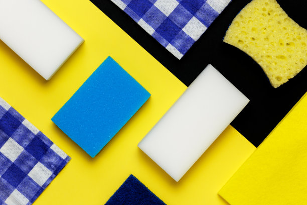卫生清洁的概念。抹布，餐巾纸，各种白色的蓝色海绵，用来擦洗和家务的灰尘在黑黄色的几何背景上俯视图。平躺图片下载