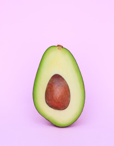 美丽的一组鳄梨切成两半，在浅粉色的背景上图片下载