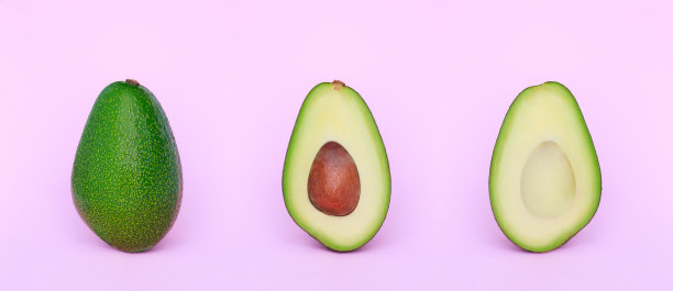 美丽的一组鳄梨切成两半，在浅粉色的背景上图片下载