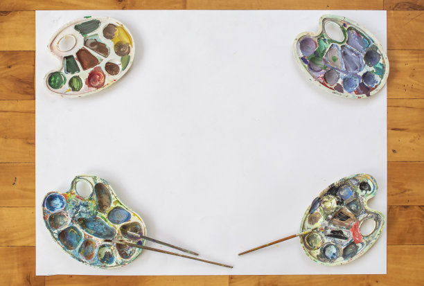 木地板上放着一张白纸和四个脏兮兮的调色板。图片下载