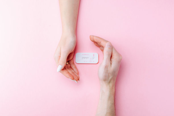 根验孕棒。女性手握阳性怀孕测试与丝带粉红色横幅背景。医疗保健妇科，孕产期产妇的观念。图片下载