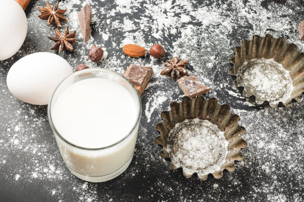 烘焙和纸杯蛋糕的原料在黑色的背景上，准备烹饪图片下载