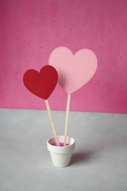 粉红色和红色的心纸在一个花盆在粉红色和灰色的背景图片下载