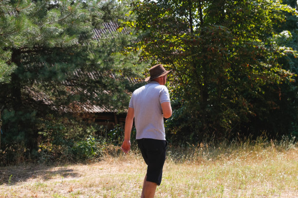 男性在帽子。微笑的农民的肖像与绿色的草地和树木的背景。一个戴着牛仔帽的年轻人。特写镜头。快乐的人。夏季男性的人。牧场主走在森林里图片下载