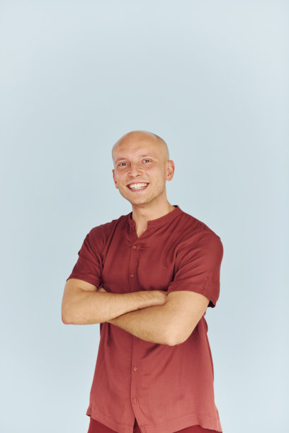 双手交叉。身穿红色休闲衬衫的男子站在白色的背景下图片下载