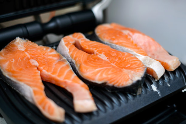 三份生三文鱼排在现代电动不粘烤架上烤。健康饮食的概念。用选择性聚焦的特写照片图片下载