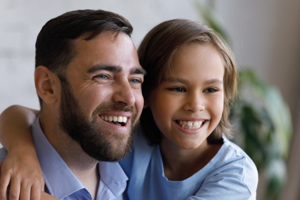 快乐的年轻父亲和小男孩看着远方。图片下载