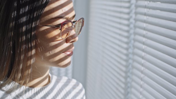 在2019冠状病毒病(COVID-19)封锁期间，一名妇女在家中透过窗户观看。图片下载