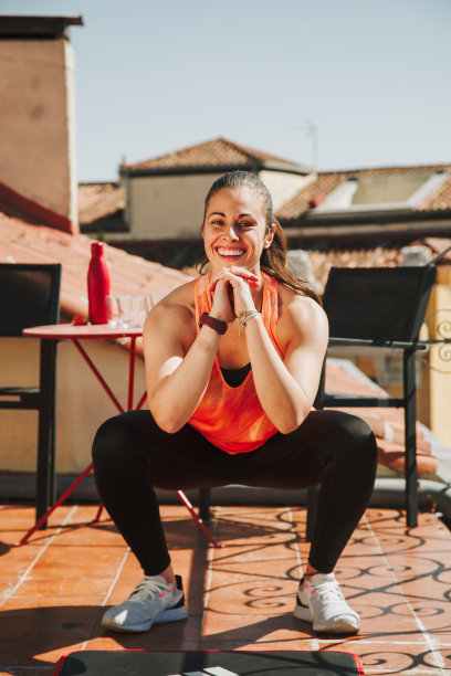 一个女人在楼顶露台上做深蹲运动图片下载