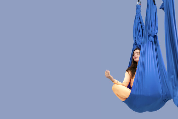 漂亮的女人在健身房做瑜伽伸展运动，在空中瑜伽吊床莲花位置冥想，横幅，为你的文本的自由空间图片下载