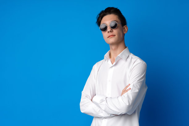 一个微笑的少年在蓝色背景下的肖像图片下载