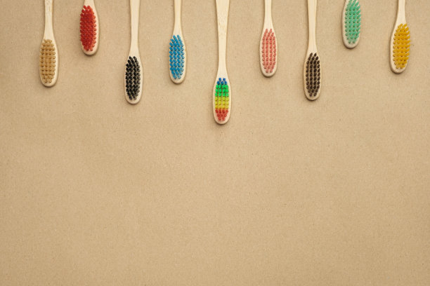 一串五颜六色的竹制牙刷挂在画框的顶部。在牛皮纸上，俯视图，拷贝空间图片下载