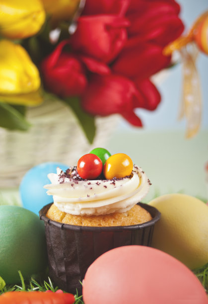 复活节纸杯蛋糕，上面有彩色彩蛋。春天的花在背景上的郁金香。复活节庆祝喜庆餐桌。图片下载