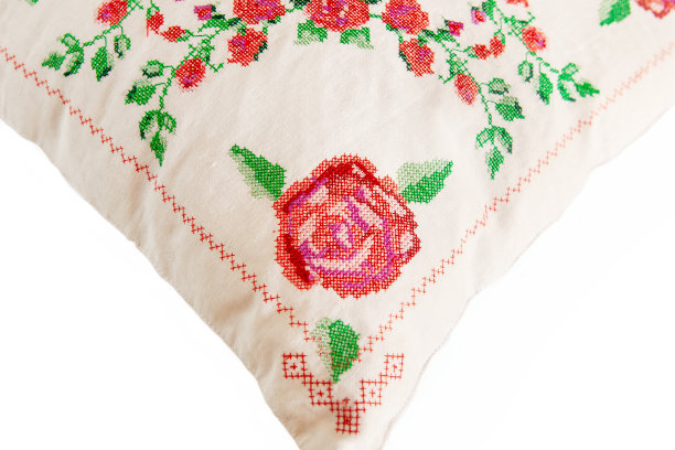 装饰元素，十字绣玫瑰花，在白色亚麻布织物上。绣花机,特写。图片下载
