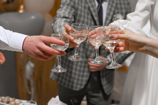 人们庆祝并举起酒杯祝酒。婚礼上的客人喝香槟酒图片下载