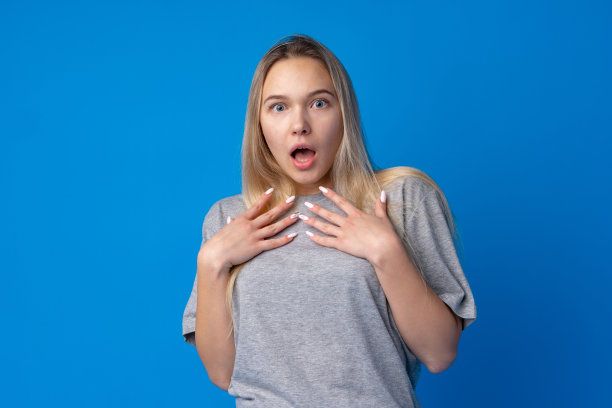 震惊和惊讶的年轻少女在蓝色的背景下图片下载