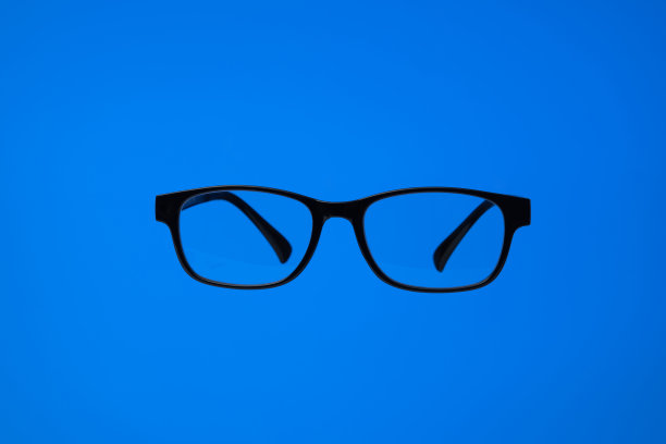 黑色塑料框眼镜。近景拍摄，蓝色背景，没有人图片下载