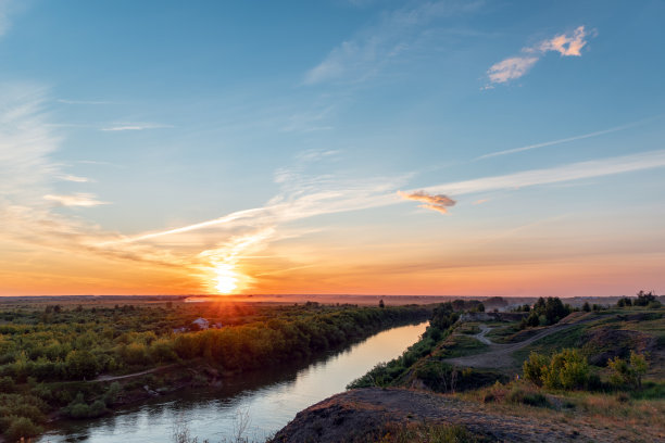 河水和森林上的天光。引人注目的夜空，云朵和阳光。傍晚日落或清晨日出的黄金时间。卷云的全景图图片下载