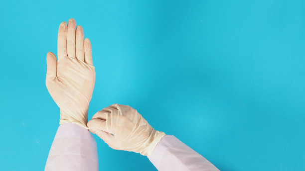 前视图。医生的手拉着蓝色背景的白色乳胶手套。新图片下载