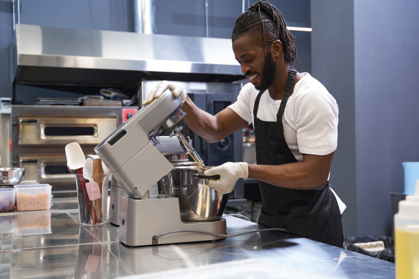 微笑的男人在厨房里做面团图片下载