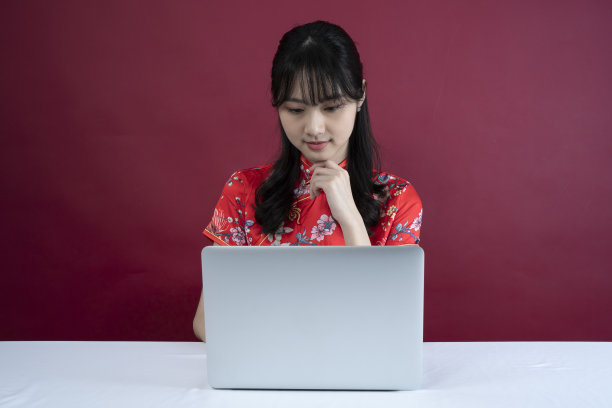 快乐亚洲年轻女子肖像，使用笔记本电脑，坐着，看着相机和期待，梦想图片下载