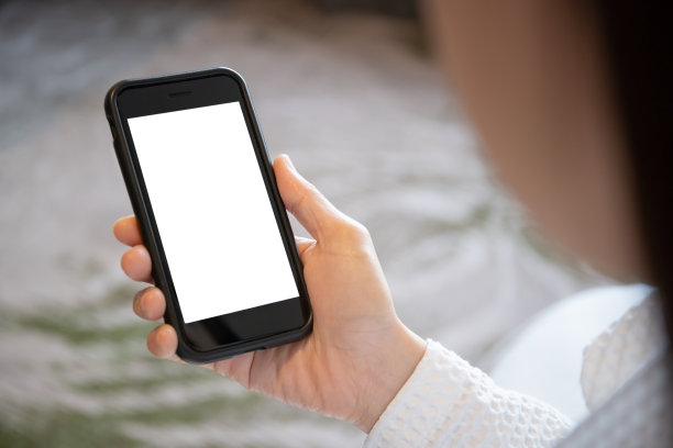 女人从床上起来使用智能手机。图片下载