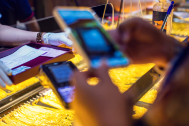 在黄金首饰店，顾客用智能手机扫描以黄金为背景的信用卡机上的二维码支付标签图片下载
