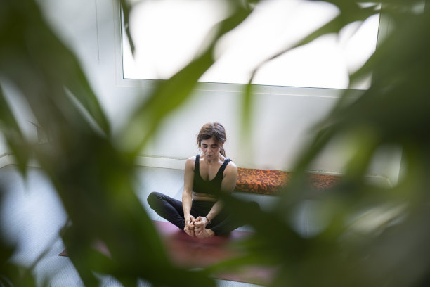 女人在背景中做瑜伽，树叶围绕着她图片下载