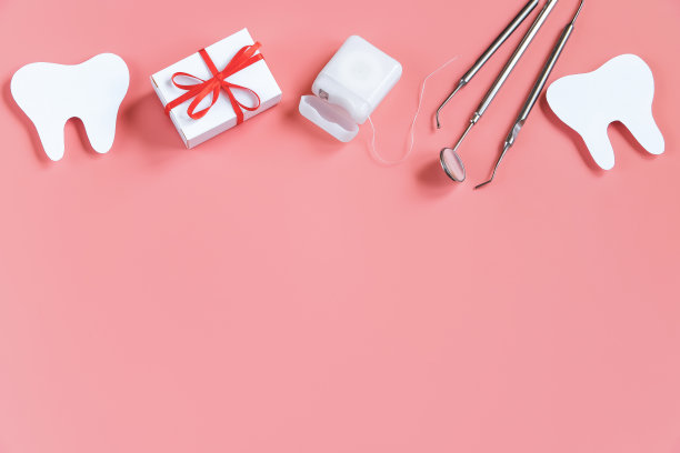 牙科保健的概念。牙科工具在粉红色的背景。牙医快乐的一天。剪纸牙齿模型。图片下载