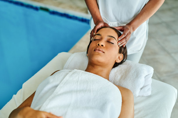 照片中一位迷人的年轻女子躺在床上享受水疗中心的按摩图片下载