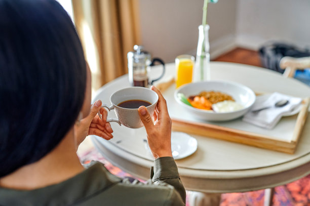 这张照片拍摄的是一个不认识的女人，早上独自坐在酒店房间里喝咖啡图片下载