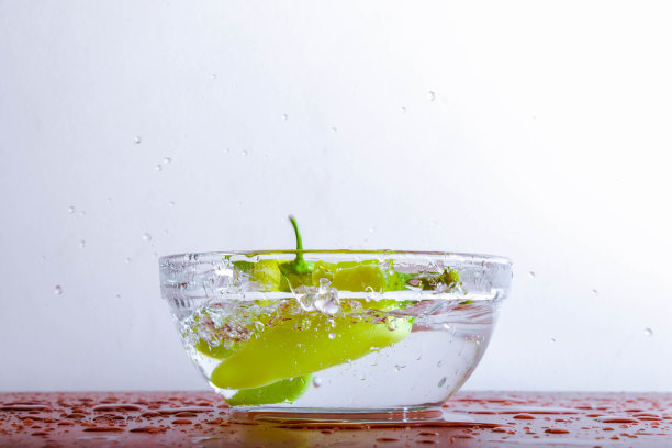 新鲜的辣椒落在一碗水中溅起水花图片下载