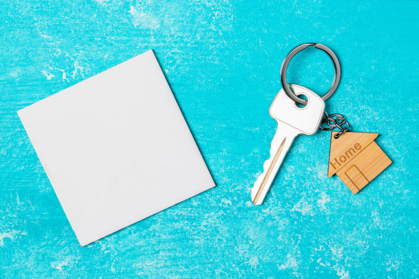 木制房子形状的钥匙链和钥匙与白色空纸蓝色木制背景图片下载