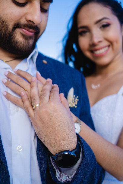 结婚戒指和背景微笑的新娘和新郎，垂直照片图片下载