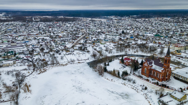俯瞰红色的天主教教堂和冬天的小镇。有教堂、房屋、河流和河岸的田园风光。图片下载