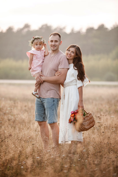 幸福家庭的画像。妈妈，爸爸和女儿走在田野里。年轻的家庭花时间在一起度假，户外。暑假的概念。母亲的，父亲的，婴儿的日子。图片下载