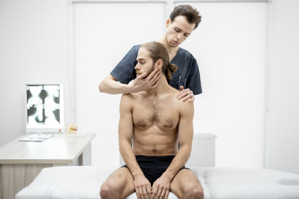 物理治疗师在医务室给一个年轻的运动员做手工治疗图片下载