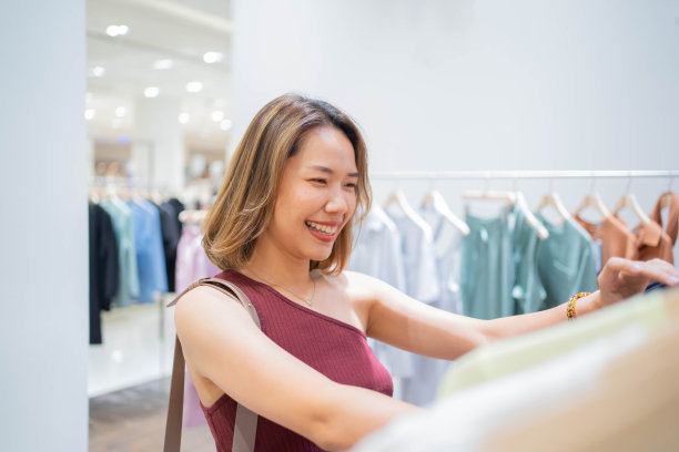 近距离的年轻女性选择服装或精品服装在百货商店的时尚商店区为城市生活方式和购物狂的概念图片下载