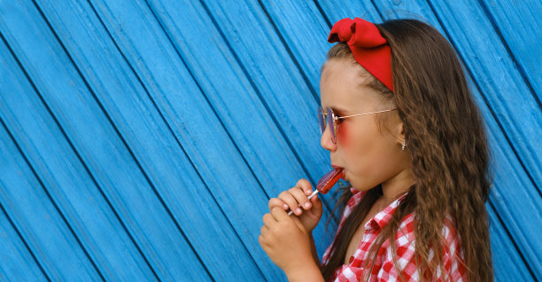 一个美丽的卷发女孩的侧面，嘴里叼着棒棒糖图片下载