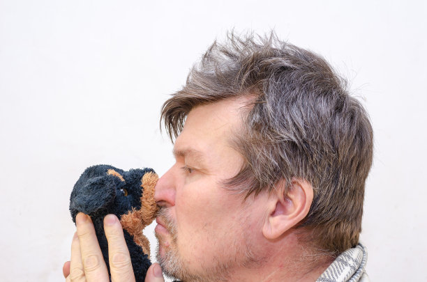 一个脸上挂着小狗玩具的男人的侧面。图片下载