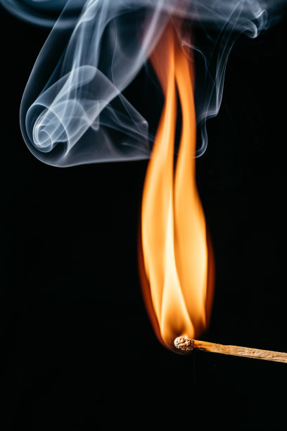 一根点燃的火柴棒在黑色背景前的特写图片下载