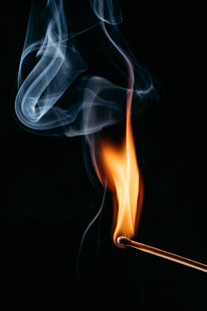 一根点燃的火柴棒在黑色背景前的特写图片下载