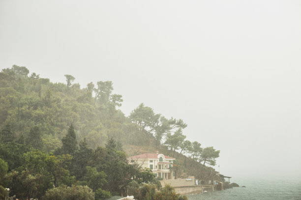 在多云的天空下，海滨别墅上下着大雨图片下载