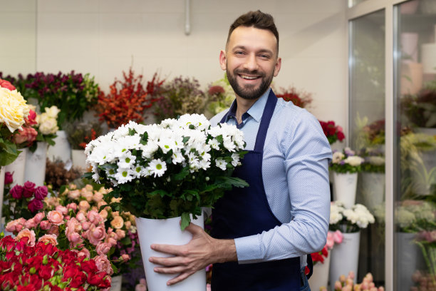 一个兴高采烈的花商，手里拿着一束花，背景是放着鲜花的冰箱图片下载